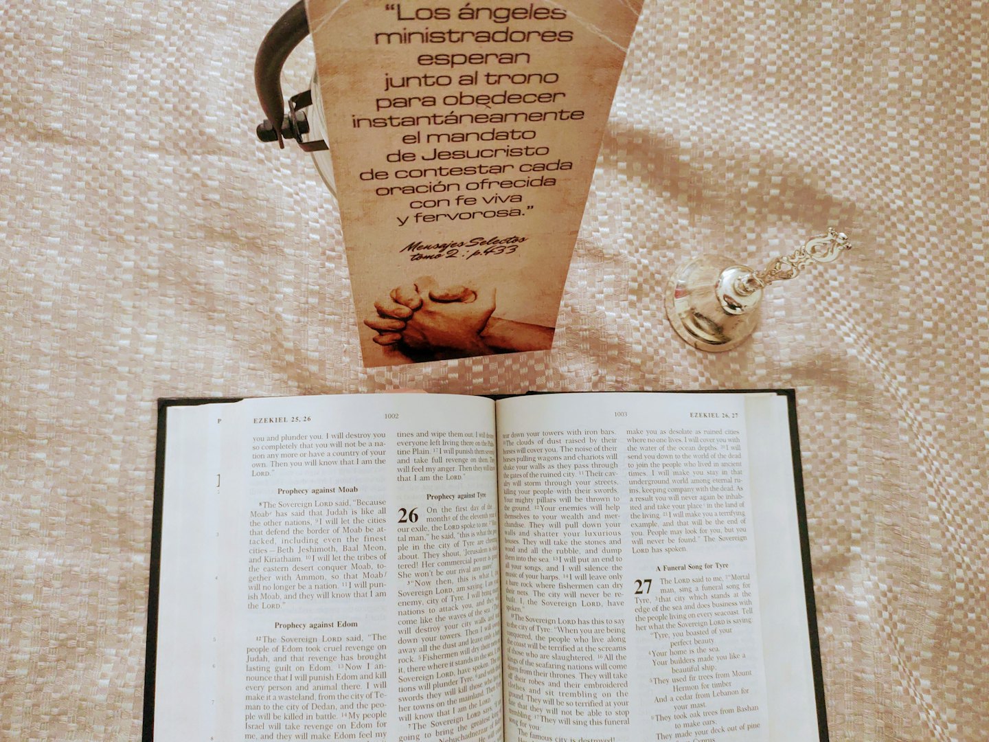 An open Bible and devotional card sit on beige fabric.