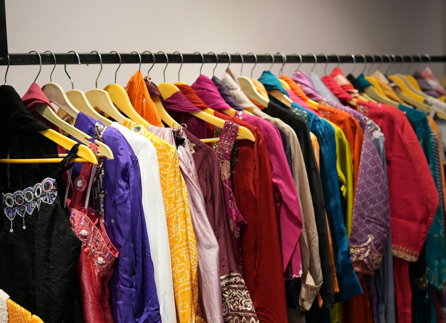 Traditional kurtas and dresses hang neatly on a clothing rack.