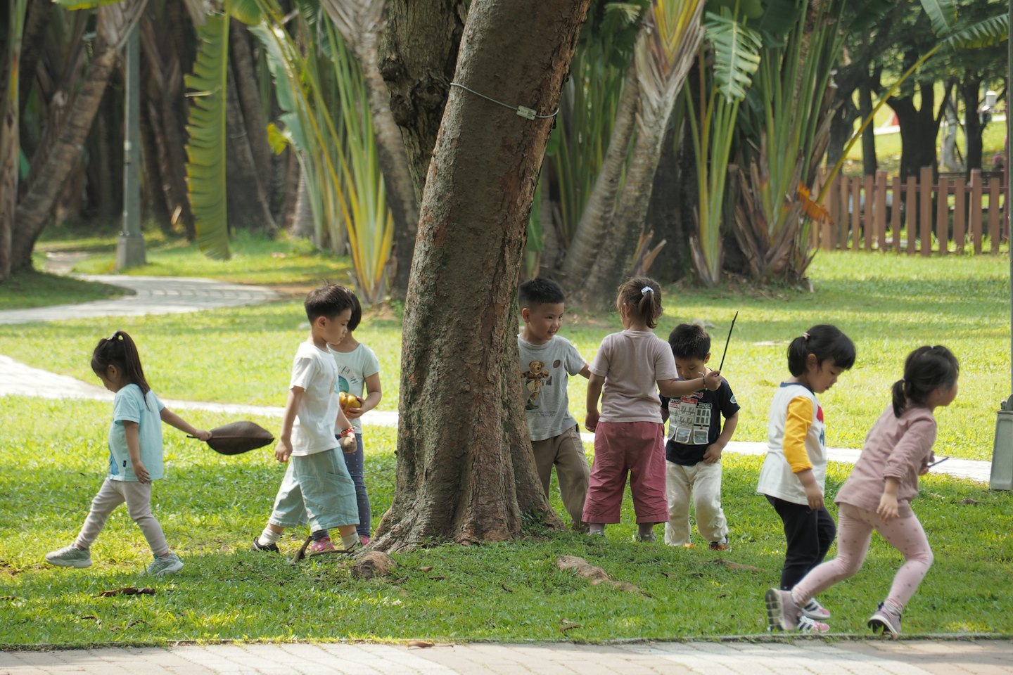 Children play and explore together in a grassy park.