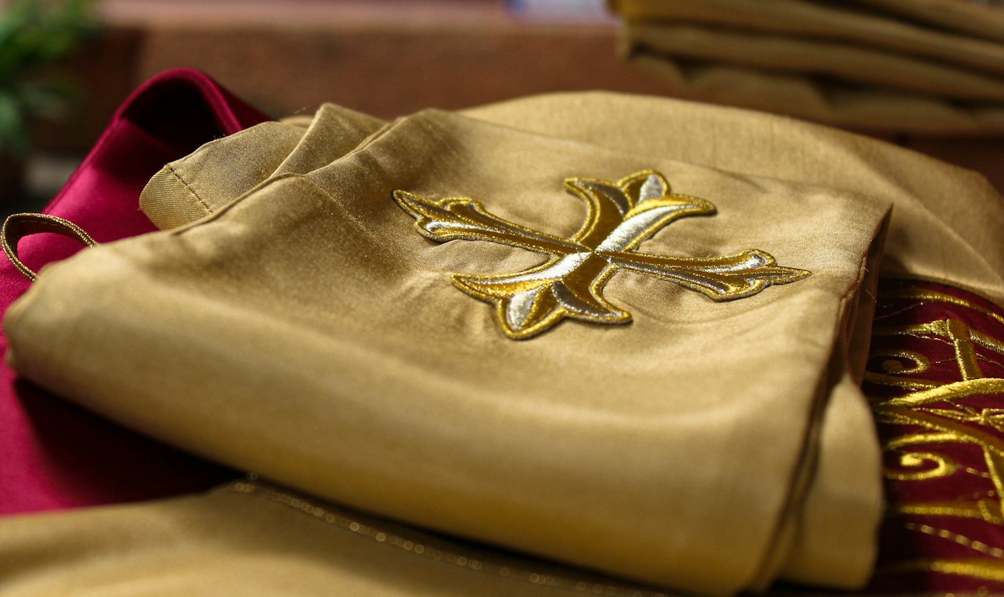 Gold satin fabric with gold and silver embroidered cross.